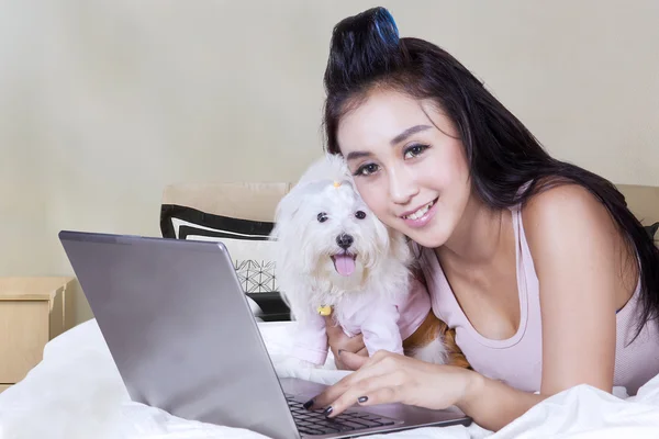 Atractiva mujer y perro con portátil en la cama —  Fotos de Stock