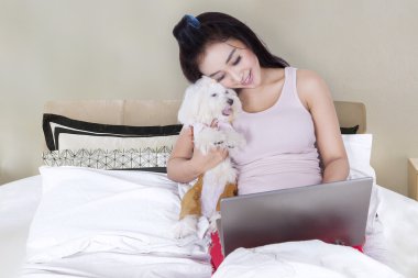 Yatakta onun köpeği ile dizüstü bilgisayar kullanan güzel kız