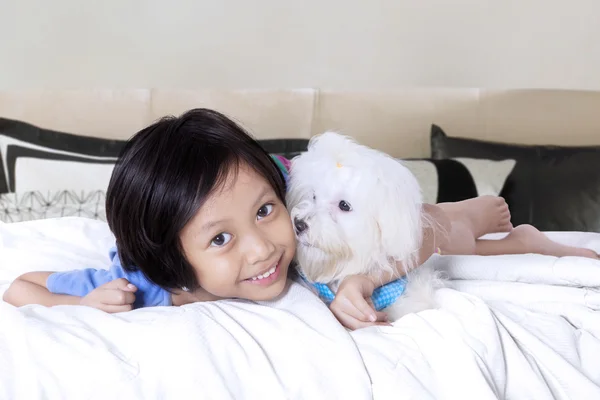 Fröhliches Mädchen umarmt maltesischen Hund auf dem Bett — Stockfoto