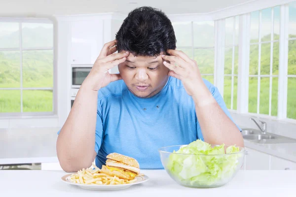 Homme confus de choisir un hamburger ou une salade — Photo