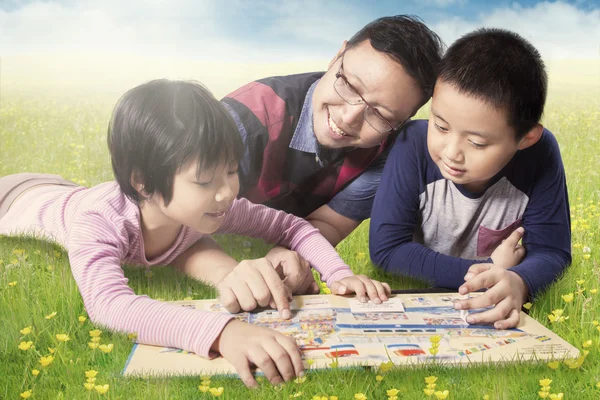 Livre de lecture familiale tout en étant couché sur la prairie — Photo