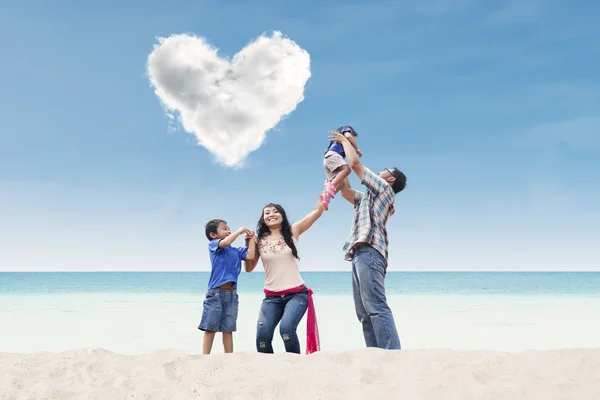 Familia bajo la nube de corazón en la playa — Foto de Stock