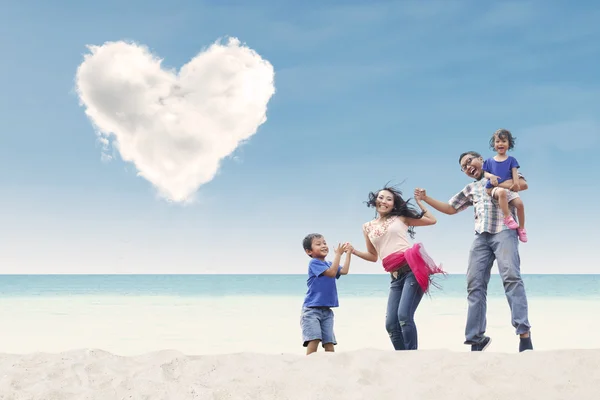 Famiglia felice in spiaggia sotto nuvola di cuore — Foto Stock