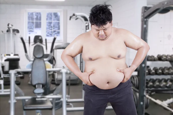 El tipo con sobrepeso sostiene su estómago en el gimnasio — Foto de Stock