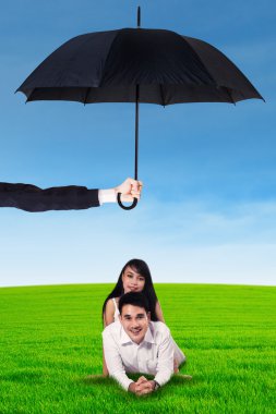 Genç çift şemsiyesi altında çim üzerinde yalan