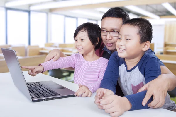 Due studenti e il loro insegnante utilizzando il computer portatile — Foto Stock