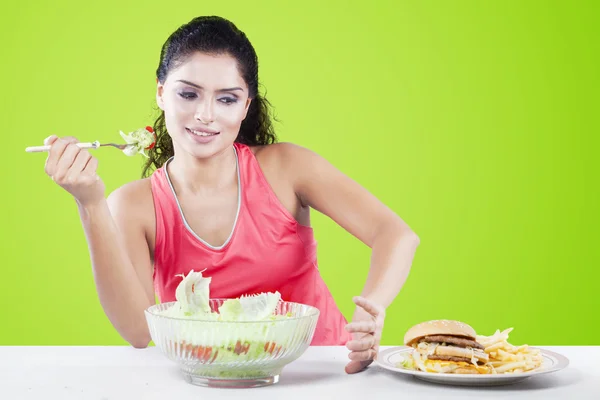 Mujer eligiendo comida rápida en lugar de una ensalada — Foto de Stock