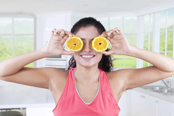 Mulher usando fatias de laranja para fechar os olhos — Fotografia de Stock