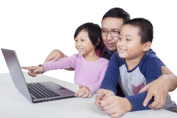 Jovem e duas crianças usando laptop — Fotografia de Stock