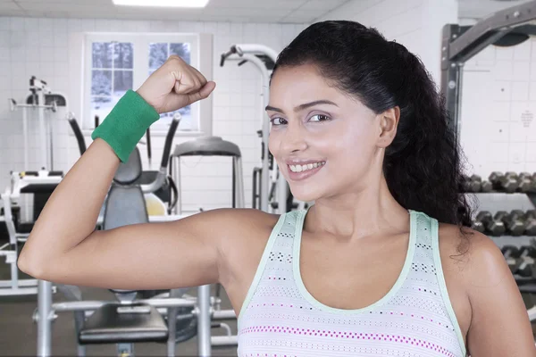 Mladá žena ukáže biceps v tělocvičně — Stock fotografie