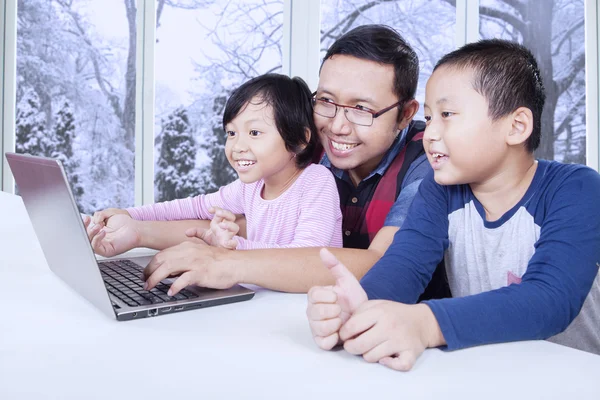 Pai com dois filhos usando laptop em casa — Fotografia de Stock