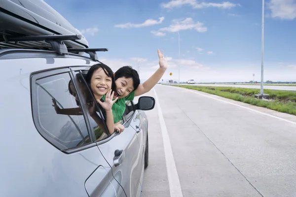 Zwei Kinder winken im Auto — Stockfoto
