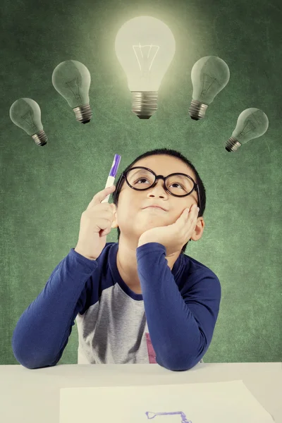 Inteligentne mały chłopiec trzyma długopis pod światło żarówka — Zdjęcie stockowe
