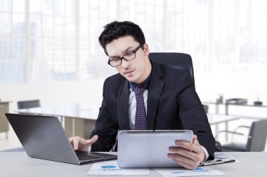 Busy caucasian worker with laptop and tablet