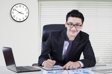Caucasian businessman with clock in office