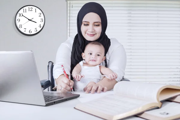 Mamma lavorando mentre tiene il suo bambino — Foto Stock