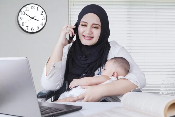 Muslimische Frau stillt ihr Baby während der Arbeit — Stockfoto