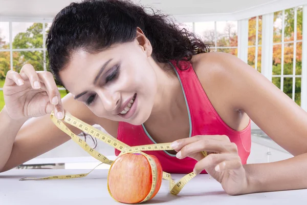 Женщина измеряет яблоко на кухне — стоковое фото
