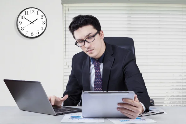 Werknemer met behulp van Tablet PC- en laptop op werkplek — Stockfoto