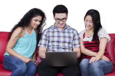 Çok etnik öğrenci kanepede dizüstü bilgisayar kullanmak