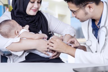 Pediatrician giving vaccine to baby boy clipart