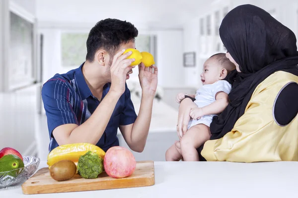 Pai usando laranjas para brincar com seu bebê — Fotografia de Stock