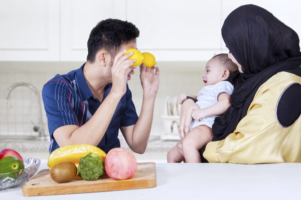 Pai brincando de frutas com bebê na cozinha — Fotografia de Stock