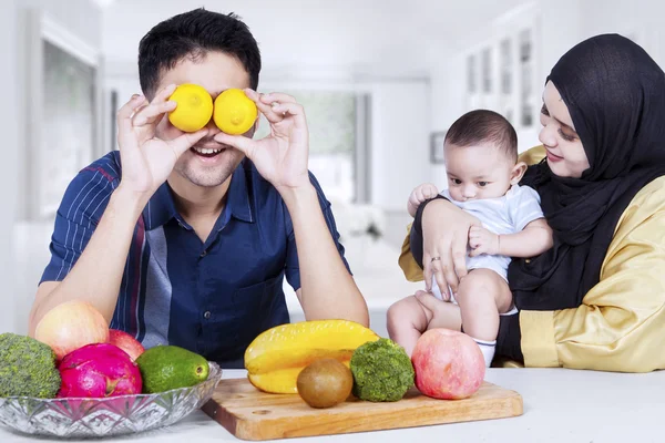 A szülők és a baba étkezőben gyümölcsökkel — Stock Fotó