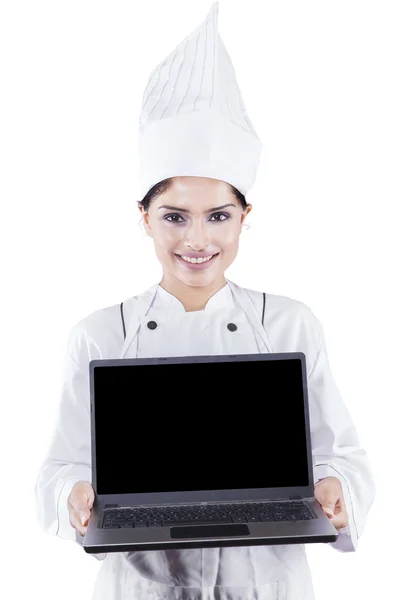 Chef bonito mostra laptop em estúdio — Fotografia de Stock