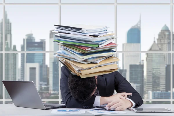 Trabalhador stressado com uma pilha de papelada — Fotografia de Stock