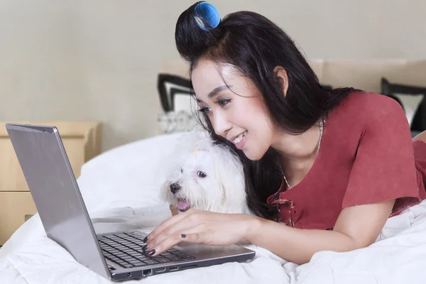 Mulher navegando na internet com cão na cama — Fotografia de Stock