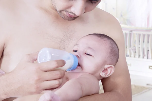 Fiatalember, etetés baba a cumisüvegről — Stock Fotó