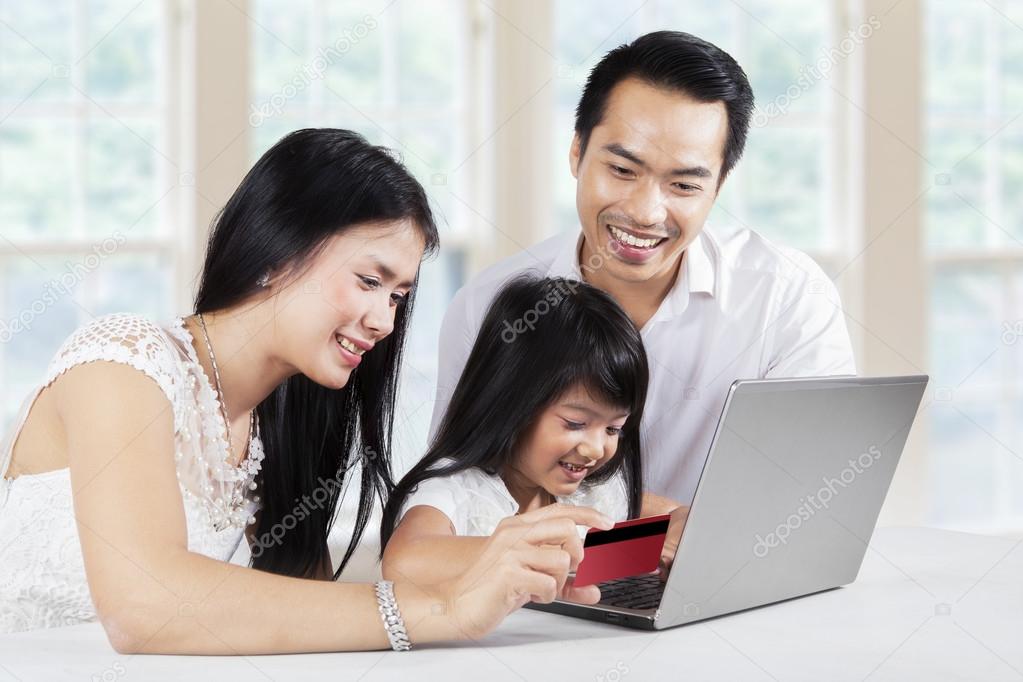 Child and her parents shopping online at home