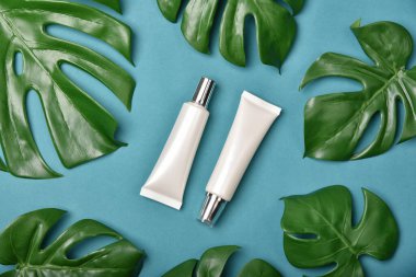 Yeşil bitkisel yapraklarla paketlenmiş kozmetik şişe kapları, organik markalaştırma için boş etiket, doğal cilt bakımı ürün konsepti.