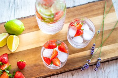 Tahta masaya çilekli ve limonlu taze içecek. Limonata ve buzlu bardaklar. Yaz içeceği.