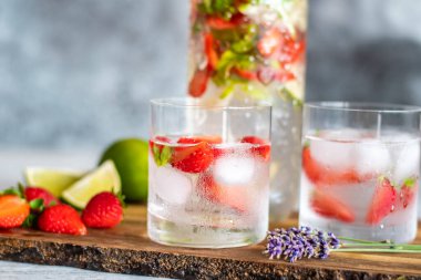 Tahta masaya çilekli ve limonlu taze içecek. Limonata ve buzlu bardaklar. Yaz içeceği.