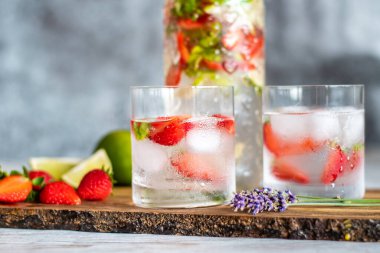 Tahta masaya çilekli ve limonlu taze içecek. Limonata ve buzlu bardaklar. Yaz içeceği.