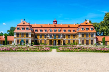 Güneşli bir yaz gününde, Rajec Jestrebi Şatosu 'nun panoramik manzarası. Mavi gökyüzü, çiçek açan pembe güller ve tarihi binanın önünde bir çeşme..