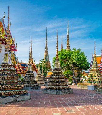 Wat Pho 'nun dış görünüşü, parlak güneşli bir günde Bangkok' ta açık mavi gökyüzünün altında parıldayan renkli çiçek seramikleriyle ve altın tapınak çatılarıyla süslenmiş..