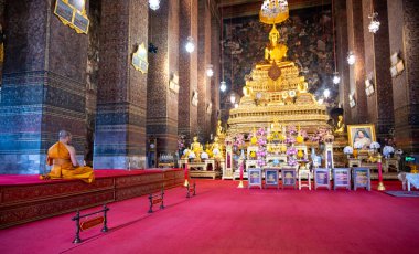 Bangkok, Tayland - 11.2025: Geleneksel turuncu cüppeli Budist keşiş bir tapınağın içinde sessizce oturmuş, huzur, bağlılık ve kutsal atmosferle sakin bir ruhani sahne yaratıyor..