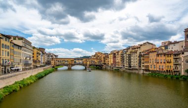 Floransa 'daki Ponte Vecchio manzarası (Ponte Vecchio, Firenze) ve Arno Nehri yakınlarındaki binalar aydınlık bir yaz gününde, tarihi cazibe ve nehir kenarı manzarasını yakalar..