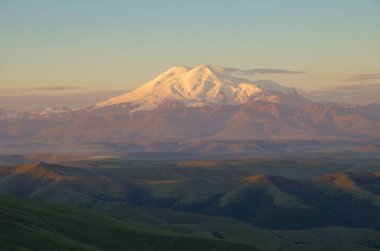 Elbrus Dağı 'nın zirvesinin manzarası gün doğumunda aydınlandı. Elbrus Dağı - Rusya ve Avrupa 'nın en yüksek ve en belirgin zirvesi. Manzara Bermamyt Platosu 'ndan. Doğa ve seyahat. Rusya, Kafkasya, Karach