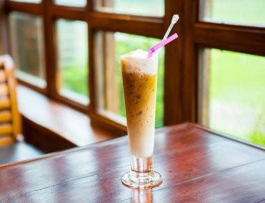 Pencerenin yanındaki uzun bardakta kahve.