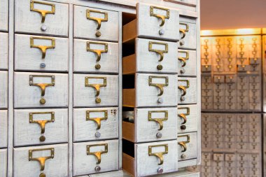 Eski bir mobilya modülünde beyaz etiketli küçük çekmeceler