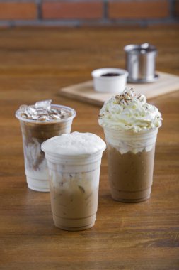 Kremalı buzlu kahve ve ahşap masada kahve çekirdekleri..