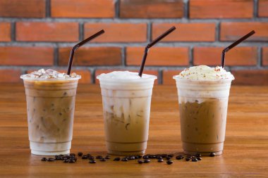 Kremalı buzlu kahve ve ahşap masada kahve çekirdekleri..