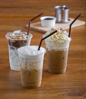 Kremalı buzlu kahve ve ahşap masada kahve çekirdekleri..