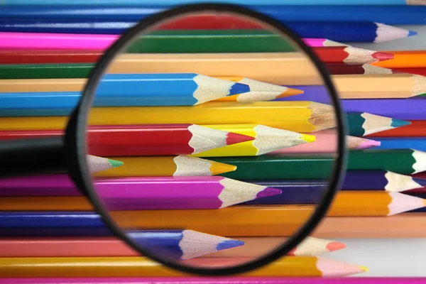 Lápis coloridos sob loop - escolha cuidadosa de cor — Fotografia de Stock