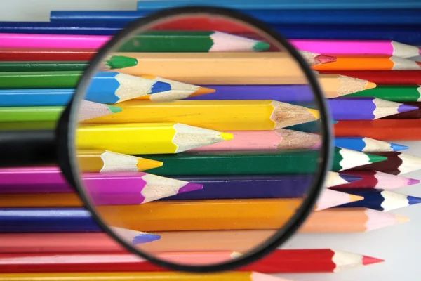 Colored pencils under loop - careful choice of color — Stock Photo, Image