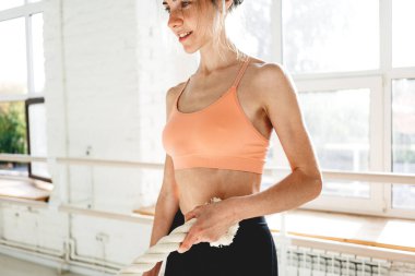 Beyaz spor salonunda idman ipleri kullanan formda bir bayan sporcu. Sporcu, savaş halatlarıyla çalışıyor.